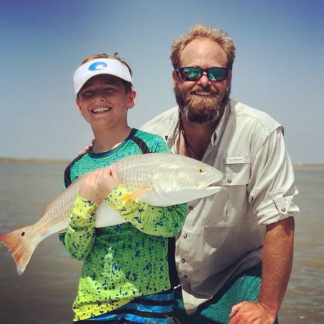 Happy-client-happy-captain Smiling Captain Ryan with a smiling kid holding a large redfish